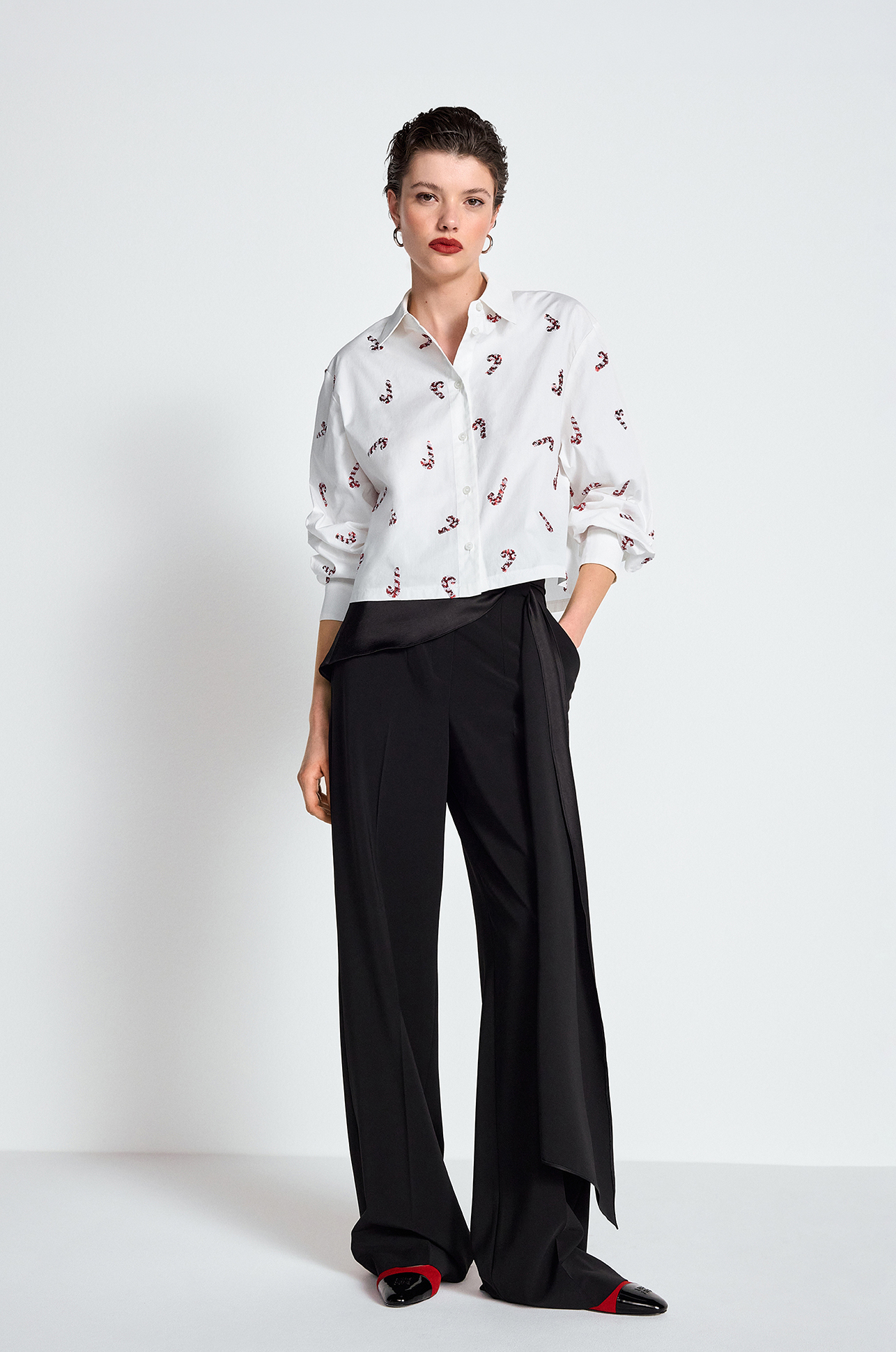 weiße Bluse, Musterprint, weite schwarze Hose, verkürzter Schnitt, rote Pumps